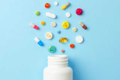 Various vitamin pills and supplements coming out of a jar
